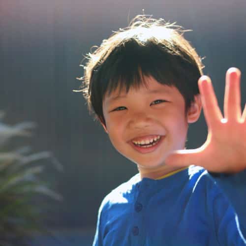 Young boy with his hand stretched out with sunlight shining on him.
